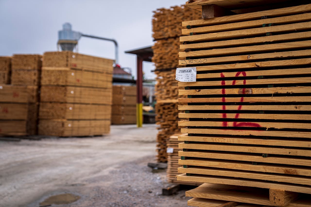 Wooden planks neatly stacked in an outdoor lumber yard, ready for shipment.